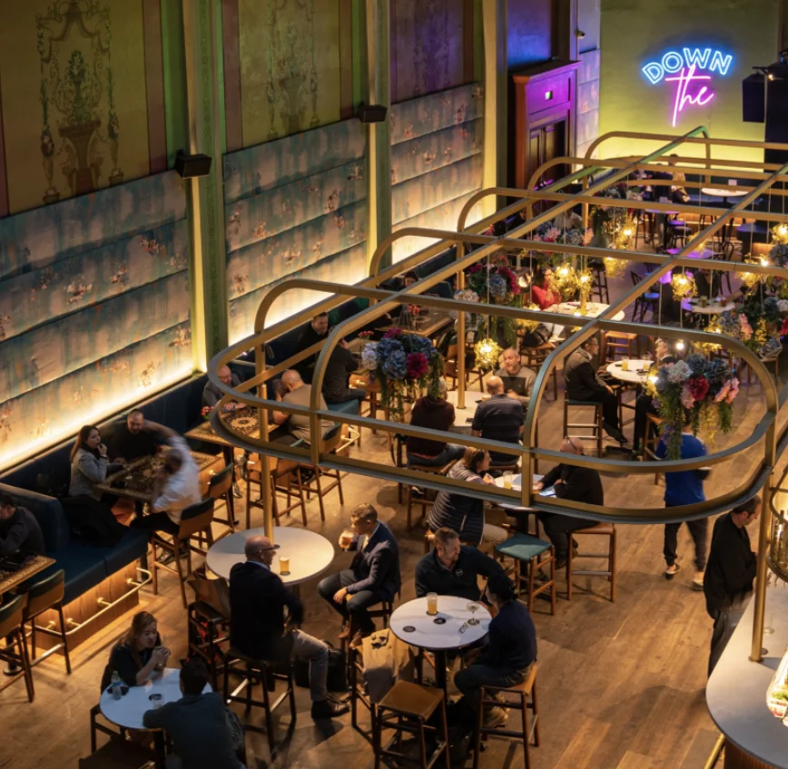 Guests seated inside Arthouse Hotel's warmly lit dining area