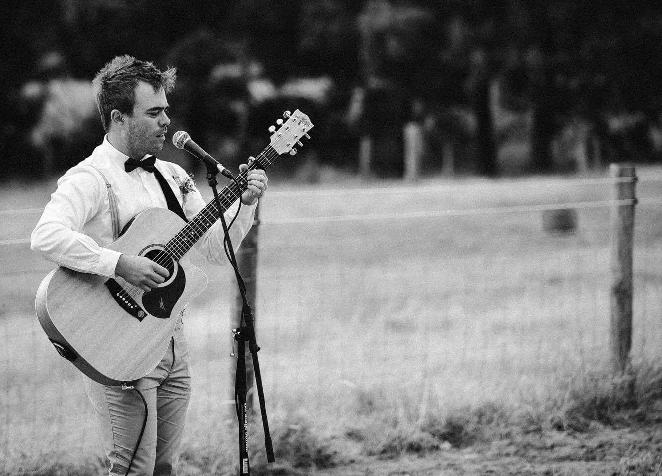 Heath performing outdoors with acoustic guitar and vocals