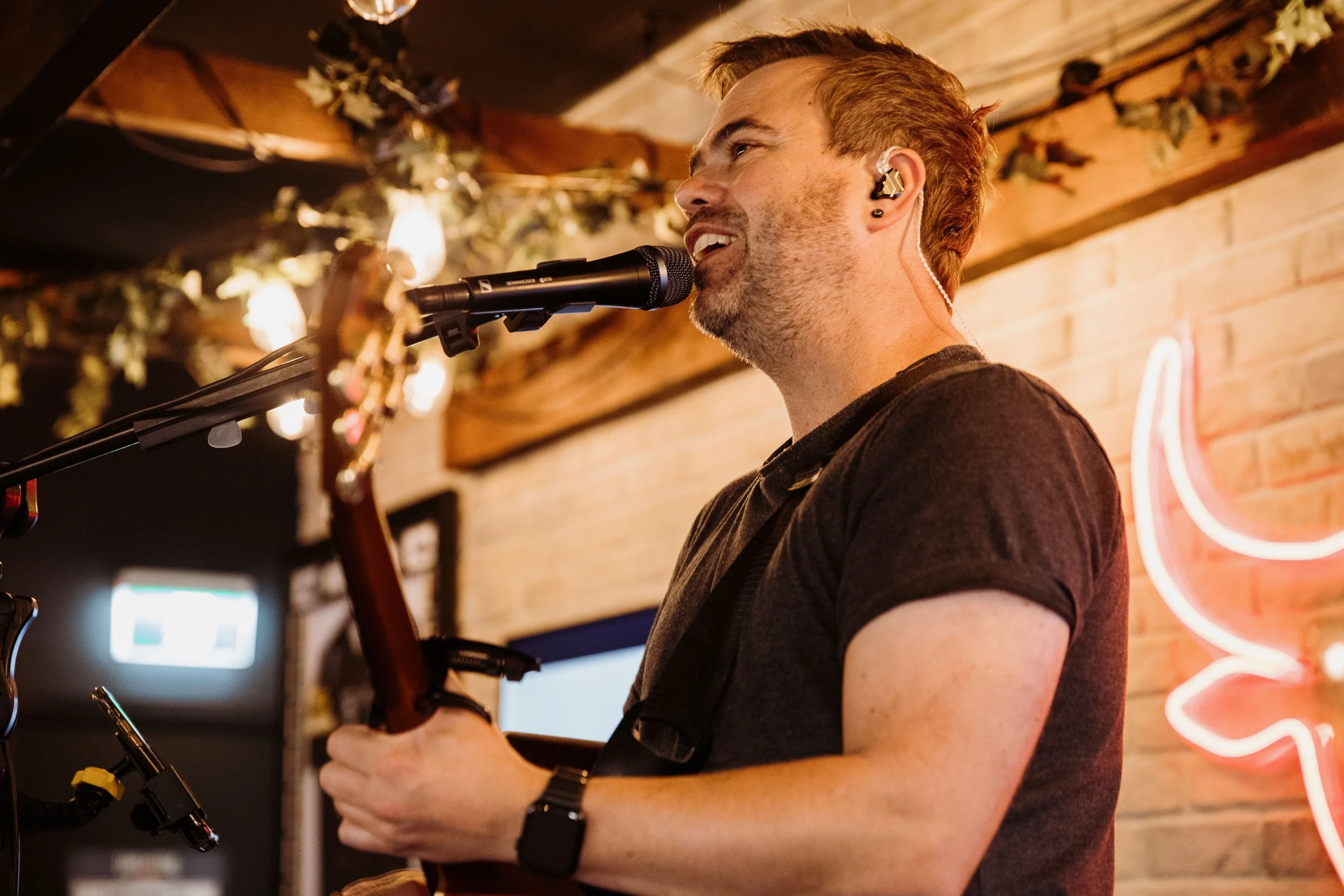Heath singing and playing guitar at a venue